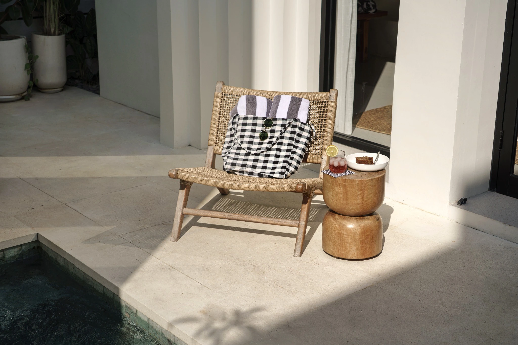 Sunlit poolside lounge chair with a checked bag, drink and snack at Lily 12